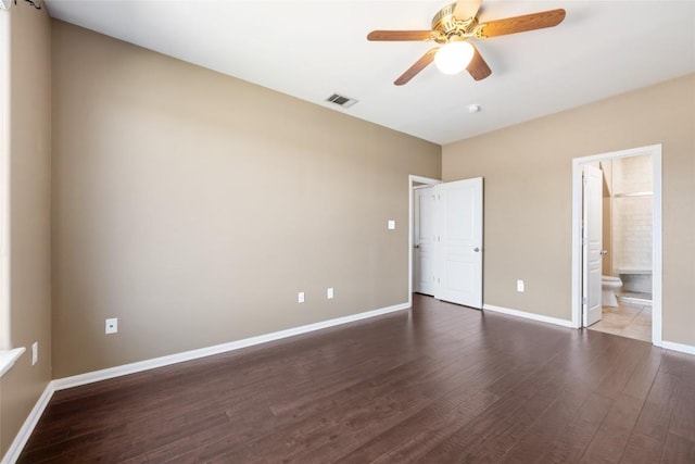 unfurnished bedroom with ensuite bath, wood finished floors, visible vents, and baseboards