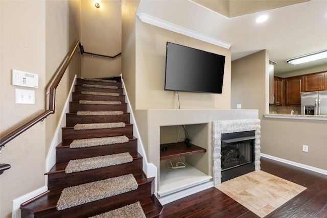 staircase featuring recessed lighting, a fireplace, baseboards, and wood finished floors