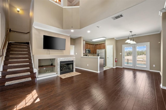 unfurnished living room featuring dark wood-type flooring, a fireplace with flush hearth, visible vents, and baseboards