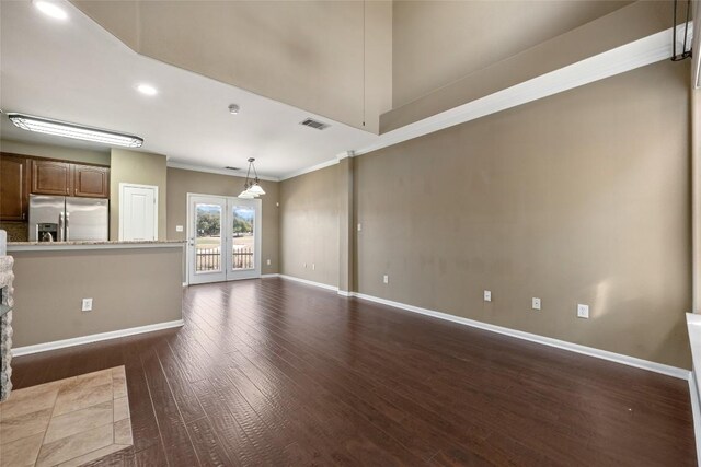 unfurnished living room with ornamental molding, dark wood-style flooring, visible vents, and baseboards