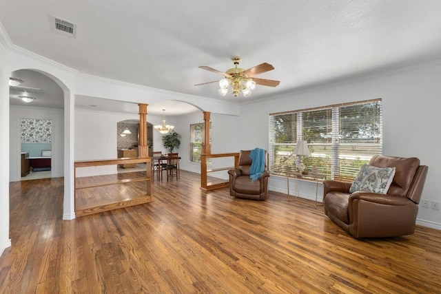 sitting room featuring arched walkways, crown molding, visible vents, wood finished floors, and ornate columns