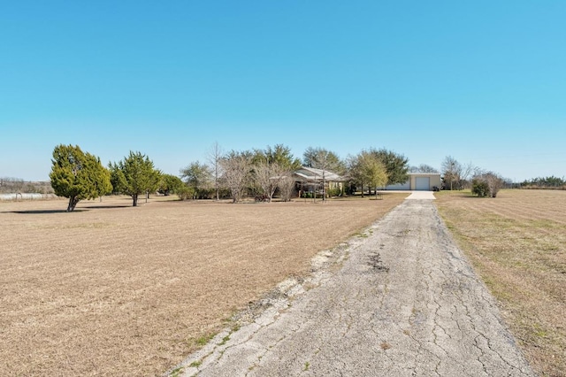 view of street with aphalt driveway and a rural view