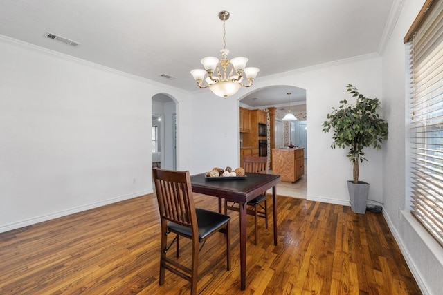 dining area with arched walkways, visible vents, ornamental molding, wood finished floors, and baseboards