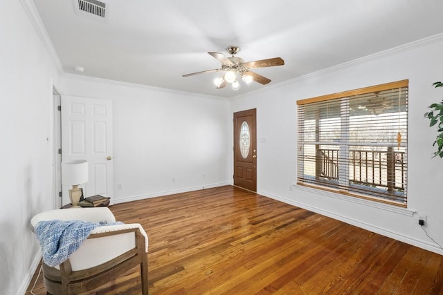 foyer featuring baseboards, visible vents, ceiling fan, ornamental molding, and wood finished floors