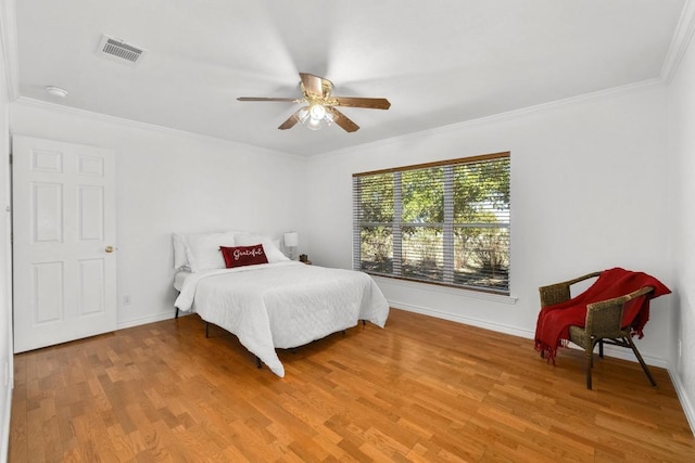 bedroom with baseboards, light wood-style flooring, visible vents, and crown molding