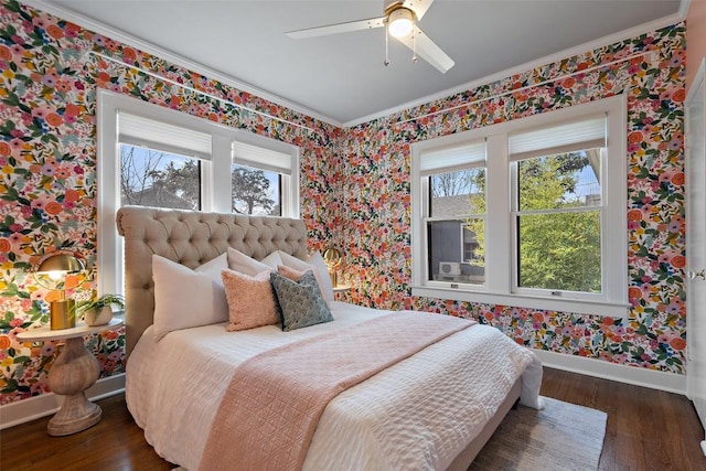 bedroom featuring baseboards, multiple windows, wood finished floors, and wallpapered walls