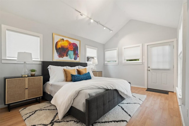 bedroom featuring lofted ceiling, light wood-type flooring, baseboards, and track lighting