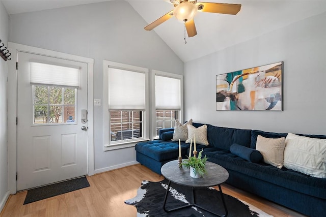 living area with a ceiling fan, lofted ceiling, light wood-style flooring, and baseboards