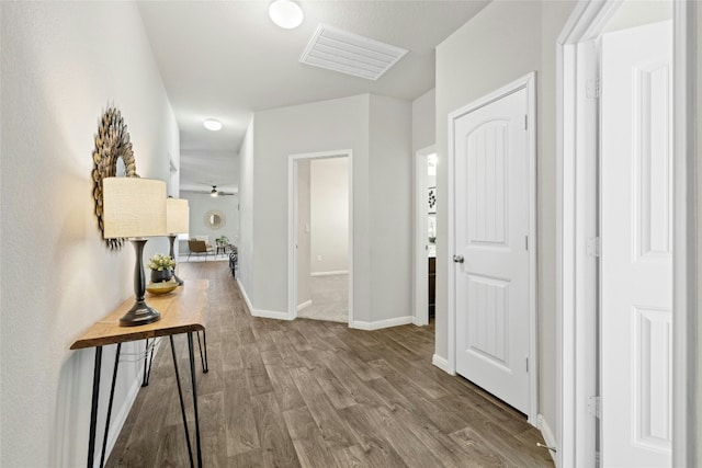 hall with visible vents, baseboards, and wood finished floors