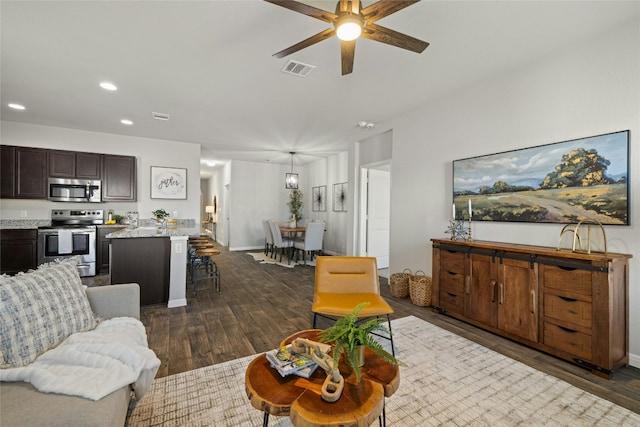 living area featuring ceiling fan, recessed lighting, dark wood-type flooring, visible vents, and baseboards