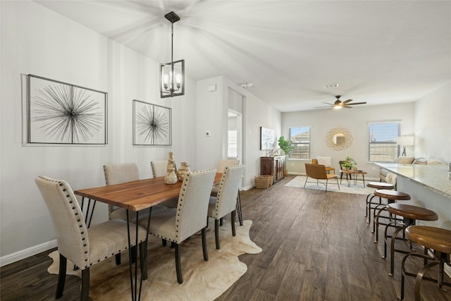 dining area featuring ceiling fan with notable chandelier, dark wood-type flooring, visible vents, and baseboards