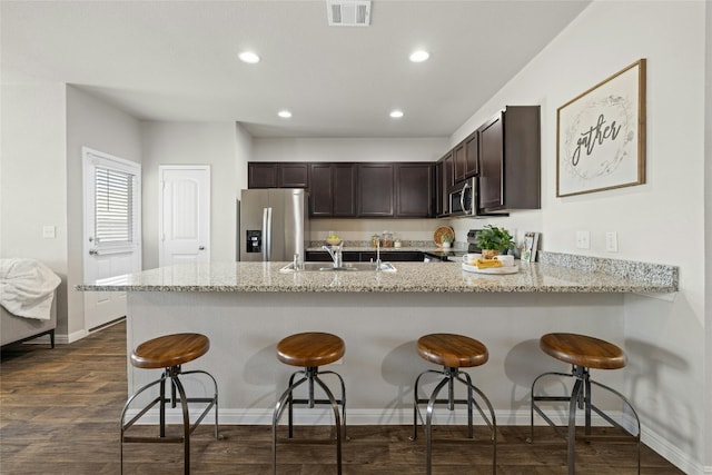 kitchen featuring visible vents, appliances with stainless steel finishes, a sink, dark brown cabinets, and a peninsula