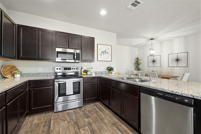 kitchen with dark wood finished floors, stainless steel appliances, visible vents, a sink, and a peninsula