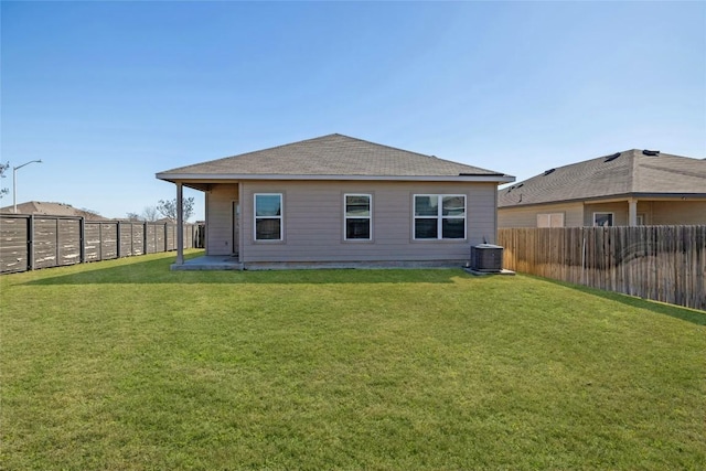 rear view of property featuring a fenced backyard, central AC, and a yard