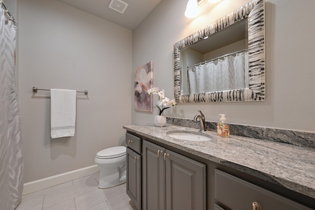 bathroom featuring tile patterned flooring, toilet, vanity, visible vents, and baseboards