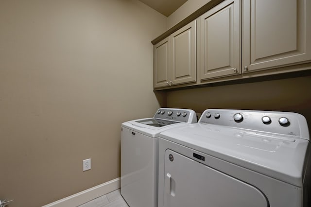 clothes washing area with washing machine and clothes dryer, cabinet space, and baseboards