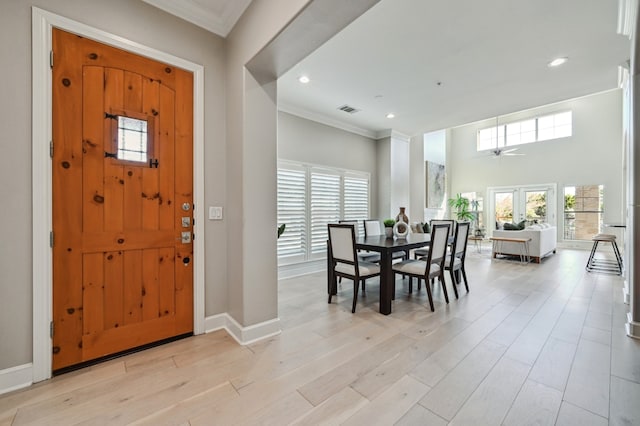 foyer featuring ornamental molding, light wood-type flooring, visible vents, and baseboards