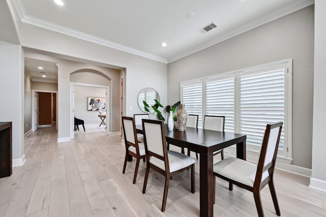 dining area with baseboards, light wood finished floors, visible vents, and crown molding