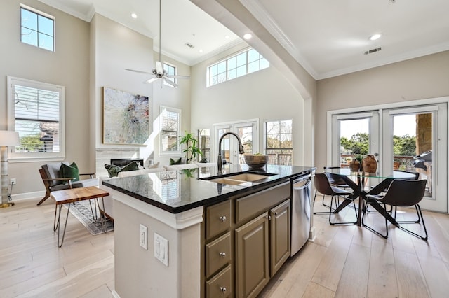 kitchen with light wood finished floors, visible vents, ornamental molding, stainless steel dishwasher, and a sink