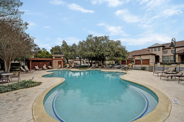 pool with a residential view, a patio area, and fence