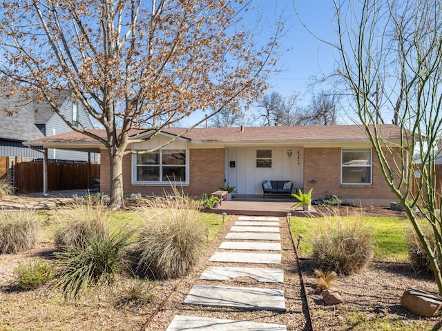 view of front facade with covered porch, brick siding, board and batten siding, and fence