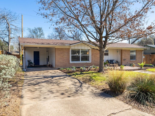 single story home featuring board and batten siding, brick siding, driveway, and fence