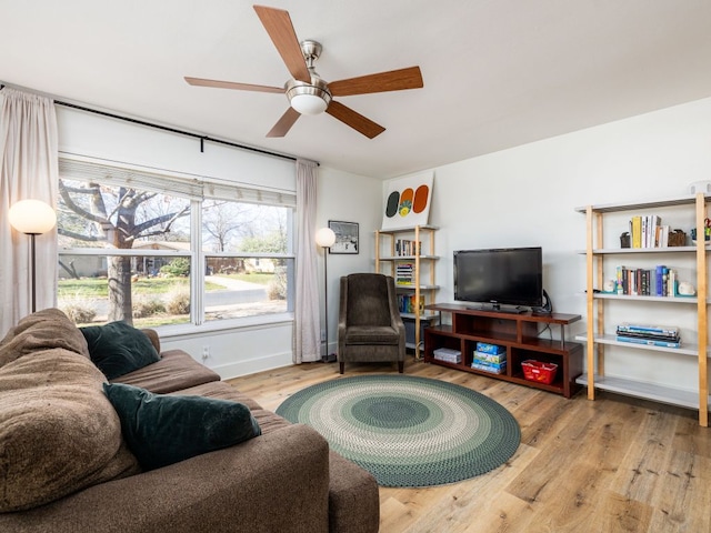 living area featuring baseboards, a ceiling fan, and wood finished floors