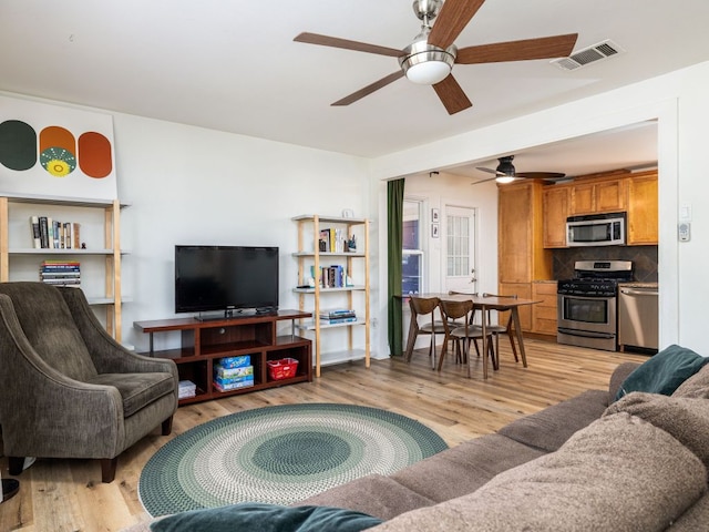 living room featuring a ceiling fan, visible vents, and light wood-style flooring