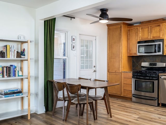 kitchen featuring ceiling fan, stainless steel appliances, light wood-style floors, brown cabinets, and decorative backsplash