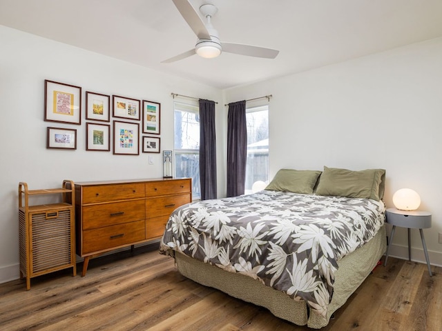 bedroom with a ceiling fan, baseboards, and wood finished floors