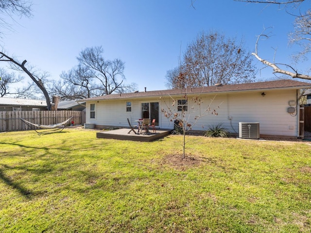 rear view of house featuring fence, central AC unit, a wooden deck, and a lawn