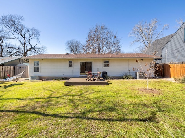 rear view of property with central AC unit, a lawn, a storage unit, fence, and an outdoor structure