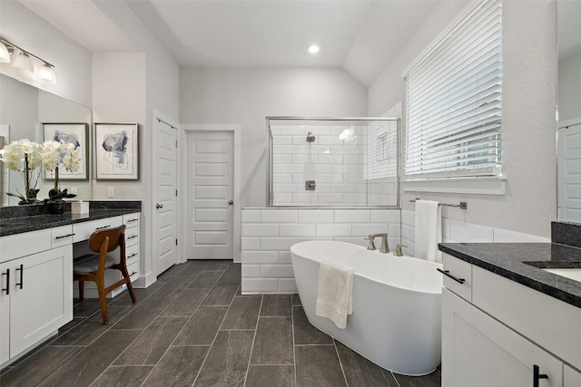 bathroom with a stall shower, lofted ceiling, a freestanding bath, vanity, and recessed lighting