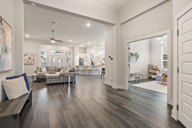 living room with dark wood-style floors, visible vents, and baseboards