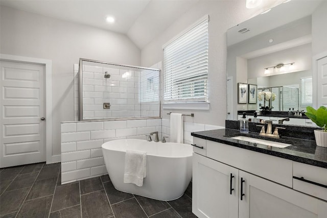 bathroom featuring lofted ceiling, visible vents, a freestanding bath, a stall shower, and vanity