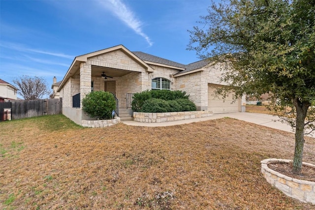 view of front of property featuring concrete driveway, an attached garage, a front yard, fence, and stone siding