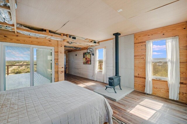 7875 W Fitzhugh Rd, Dripping Springs, TX 78620 - bedroom with wooden walls, a wood stove, wood finished floors, and access to exterior