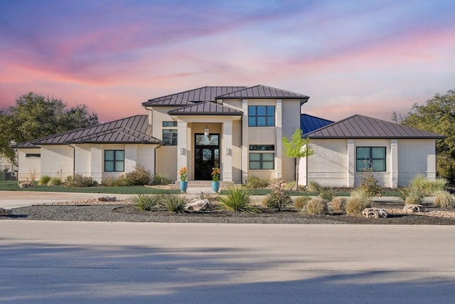 view of front of home featuring a standing seam roof, brick siding, and metal roof