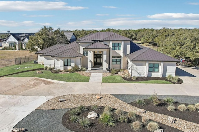 modern inspired farmhouse featuring metal roof, a front lawn, a standing seam roof, and fence