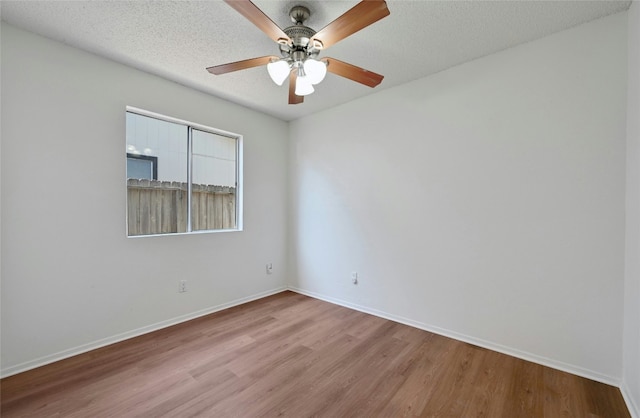 empty room with a textured ceiling, ceiling fan, wood finished floors, and baseboards