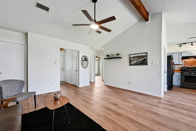 living room featuring visible vents, beamed ceiling, a textured ceiling, and light wood finished floors