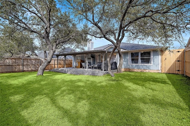 rear view of property with a patio area, a lawn, a chimney, and a fenced backyard