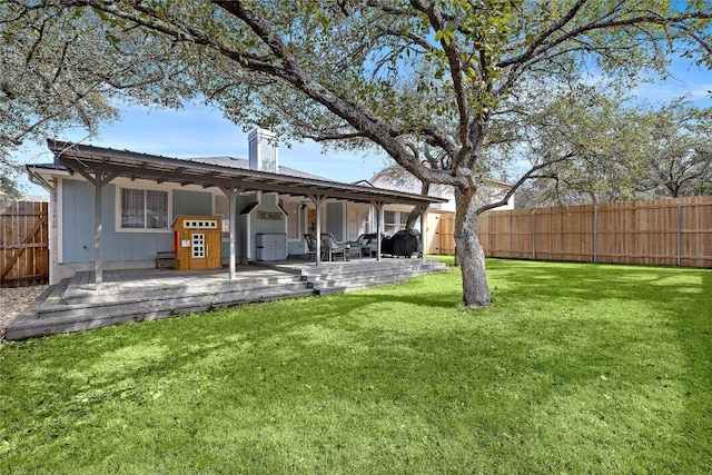 back of house featuring a deck, a yard, a chimney, and a fenced backyard