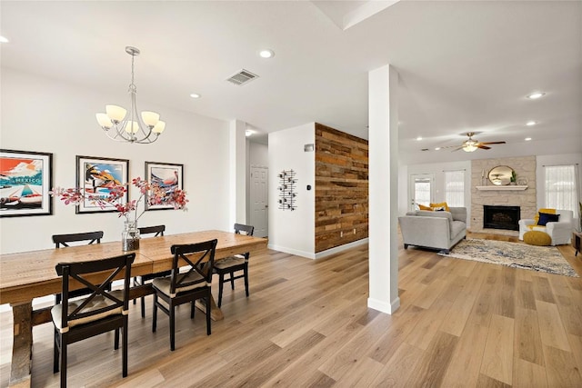 dining area with recessed lighting, light wood-style flooring, visible vents, and a stone fireplace