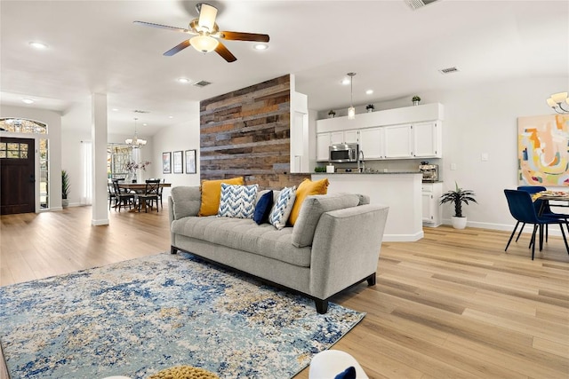 living room featuring recessed lighting, ceiling fan with notable chandelier, visible vents, baseboards, and light wood-style floors