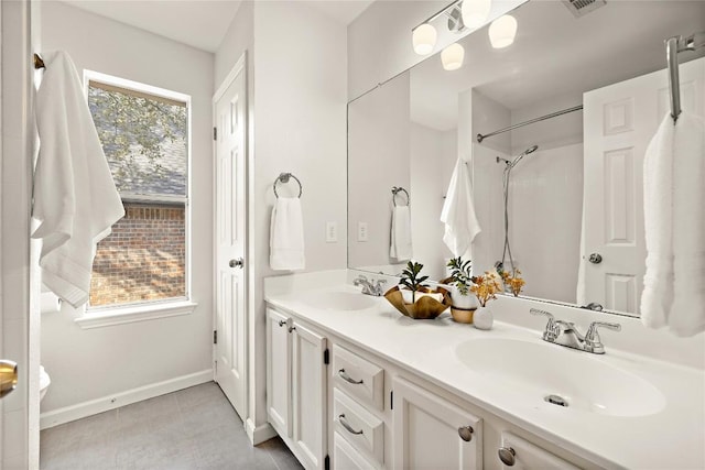 bathroom with tile patterned flooring, a sink, baseboards, and double vanity