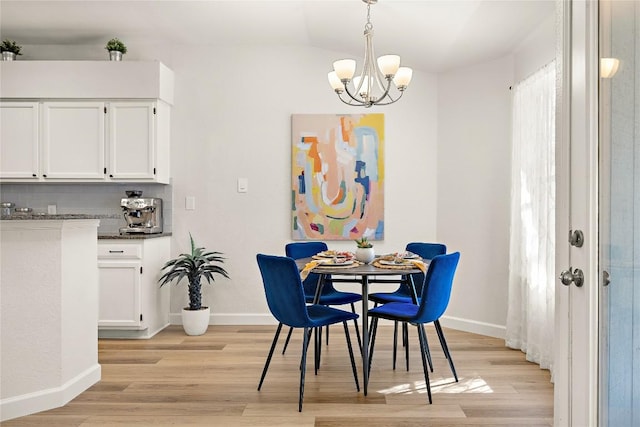 dining space with a notable chandelier, light wood-style flooring, and baseboards