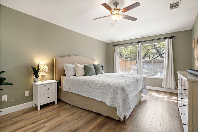 bedroom with baseboards, visible vents, a ceiling fan, vaulted ceiling, and light wood-style floors