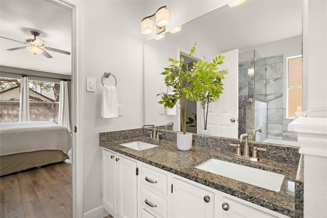 full bathroom with a stall shower, ceiling fan, a sink, and wood finished floors