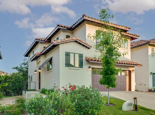 mediterranean / spanish-style home with a garage, driveway, a tiled roof, and stucco siding